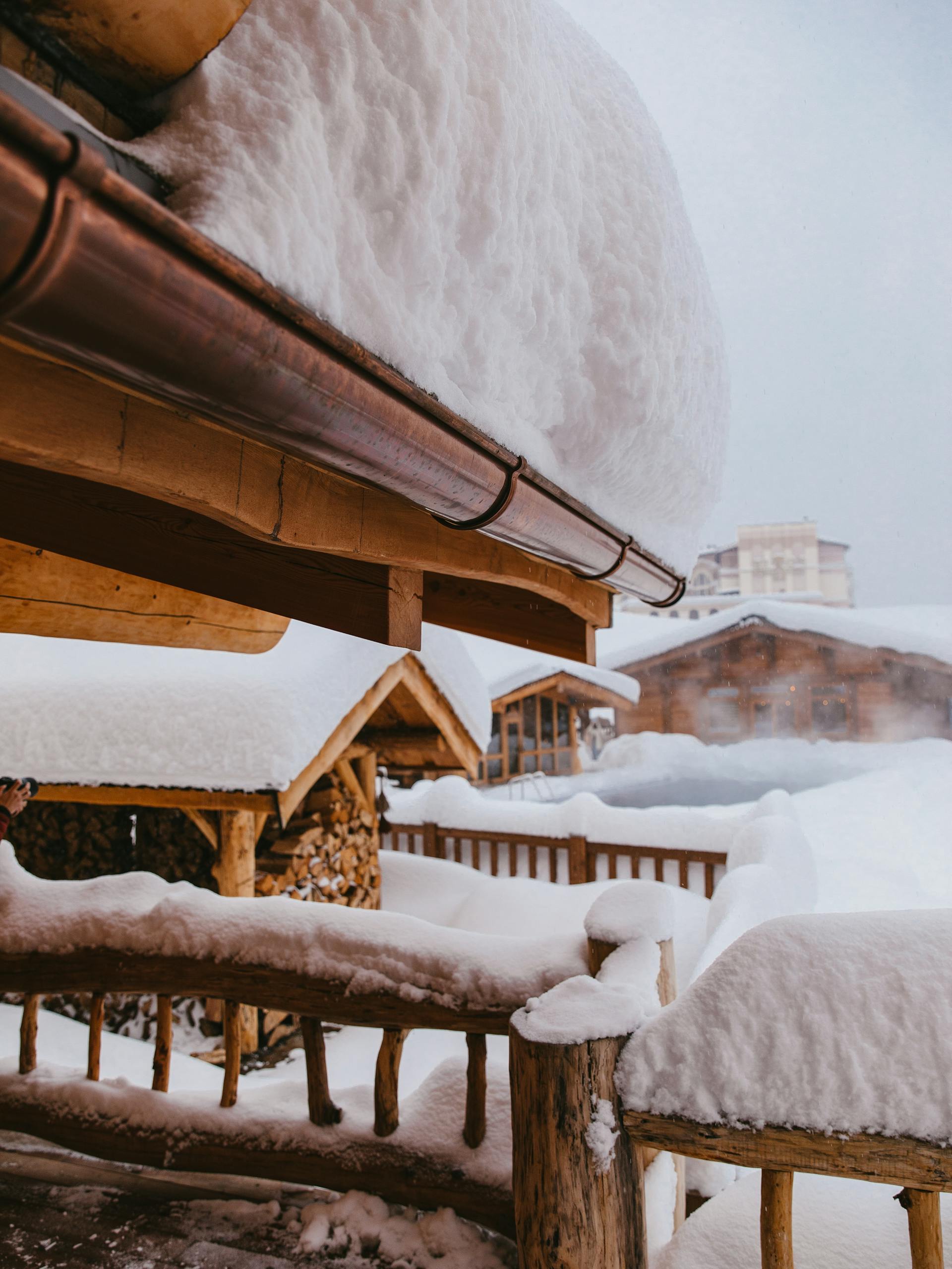 Snow-covered cabins in a serene winter landscape, evoking a cozy, rustic feel.